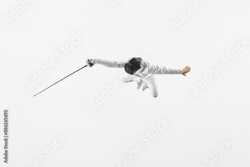 Young man, fencer in full gear lunges forward, poised to strike with their epee against white studio background. Movement. Concept of professional sport, healthy lifestyle, competition, achievement.