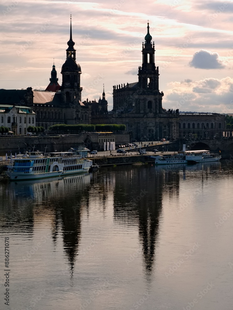 Naklejka premium Brühl's Terrace - A twilight photo of the Elbe with the Court Church and old town silhouette in the background. The high-contrast scene depicts Dresden, Saxony.