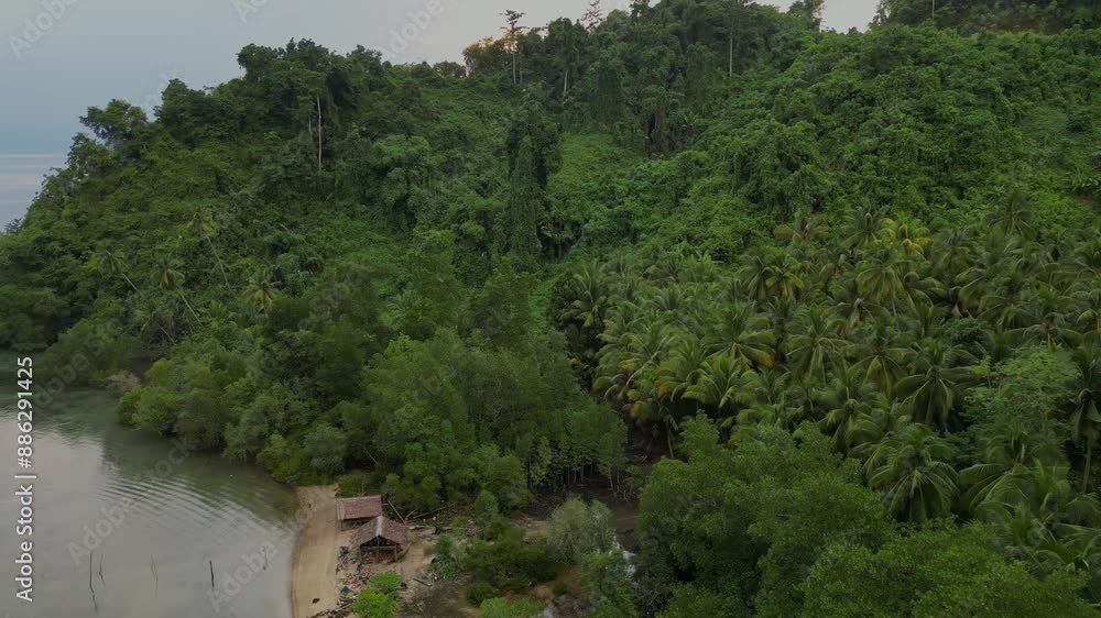 Drone flying over a remote tropical jungle island with a flat and calm ocean in the background Drone flying over a remote tropical jungle island with a flat and calm ocean in the background