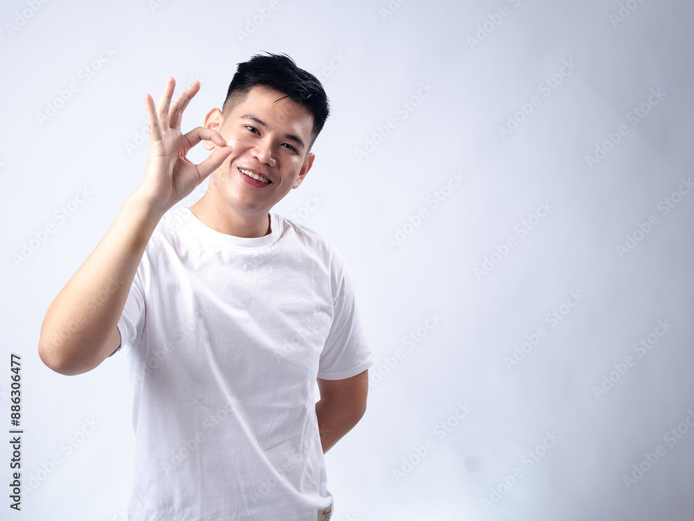 A young Asian man, wearing a white shirt, makes an A young Asian man, wearing a white shirt, makes an