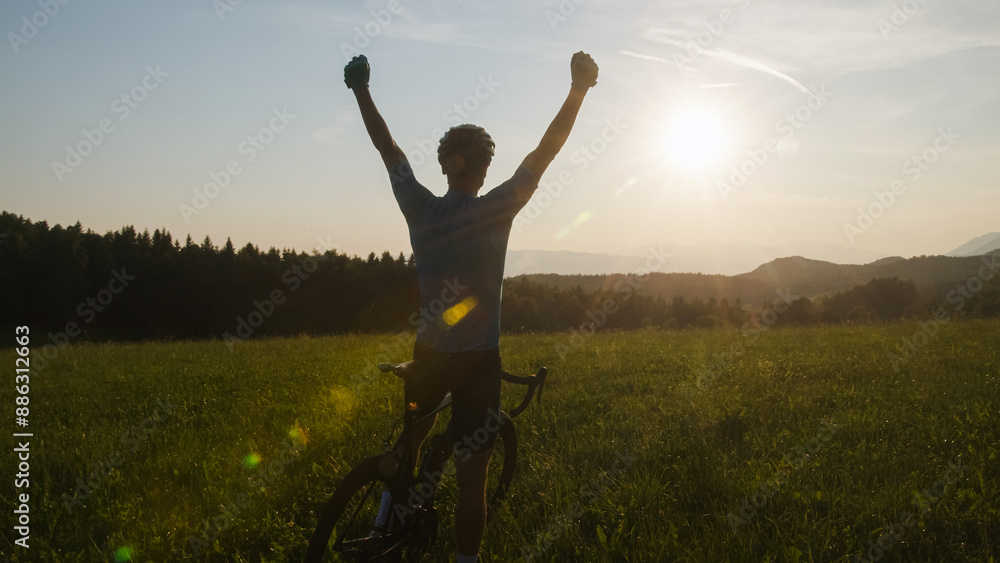 Male athlete professional racing cyclist riding a bike with arms raised above the head, in a victory pose Male athlete professional racing cyclist riding a bike with arms raised above the head, in a victory pose