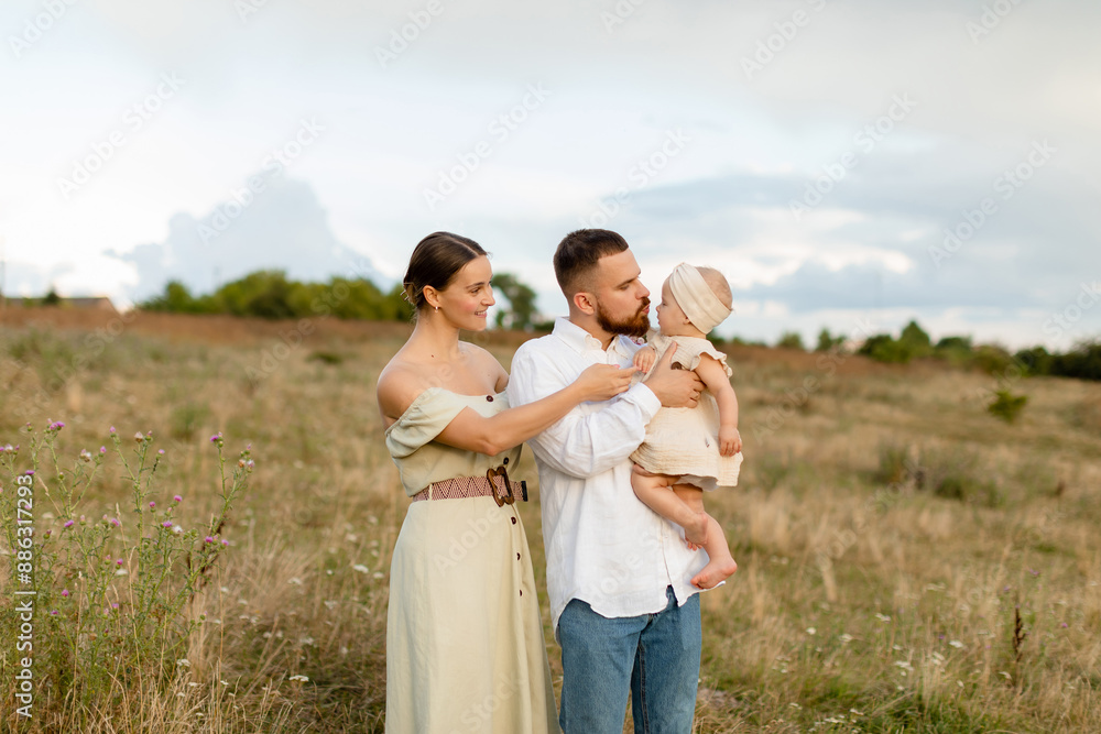 Family with a baby in nature. A woman in mint dress and a bearded man in white skirt are hugging a newborn baby girl in a beige dress in a field. Family, lifestyle concept. Family with a baby in nature. A woman in mint dress and a bearded man in white skirt are hugging a newborn baby girl in a beige dress in a field. Family, lifestyle concept.