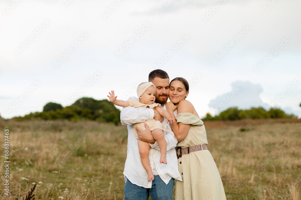 Family with a baby in nature. A woman in mint dress and a bearded man in white skirt are hugging a newborn baby girl in a beige dress in a field. Family, lifestyle concept. Family with a baby in nature. A woman in mint dress and a bearded man in white skirt are hugging a newborn baby girl in a beige dress in a field. Family, lifestyle concept.