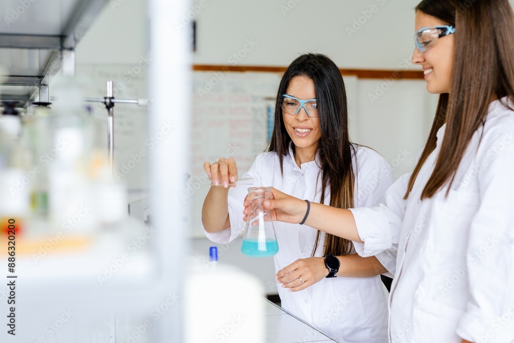 Two scientists working with chemicals in a lab beaker. Two scientists working with chemicals in a lab beaker.