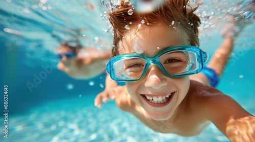 A delighted boy with blue goggles swims underwater, smiling broadly while enjoying his time in the pool, highlighting the pure joy of childhood and aquatic adventures.