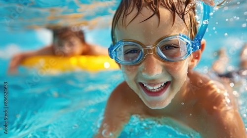 A cheerful child wearing clear goggles swims underwater in a blue pool, capturing a moment of pure enjoyment and the carefree spirit of youthful aquatic exploration.