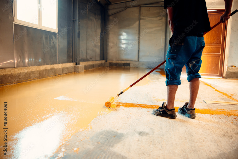 Fototapeta premium Construction worker applying epoxy resin coating on concrete floor using a roller