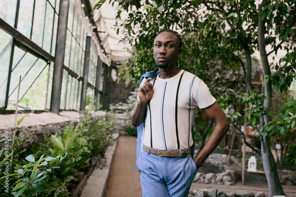 Handsome African American man in sophisticated white shirt and blue pants posing in a vivid green garden. Handsome African American man in sophisticated white shirt and blue pants posing in a vivid green garden.