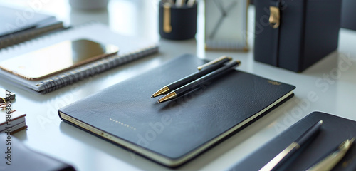 An elegantly arranged desk with a variety of premium stationery items including notebooks, pens, and paperclips. photo