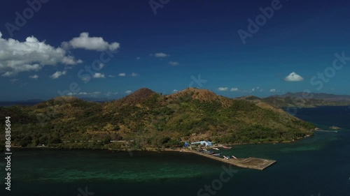 Early morning drone flight approaching Bancuan Island in Coron, Philippines. The video captures the island's vibrant landscape highlighted by the striking colors of the sky and sea at dawn, creating a photo