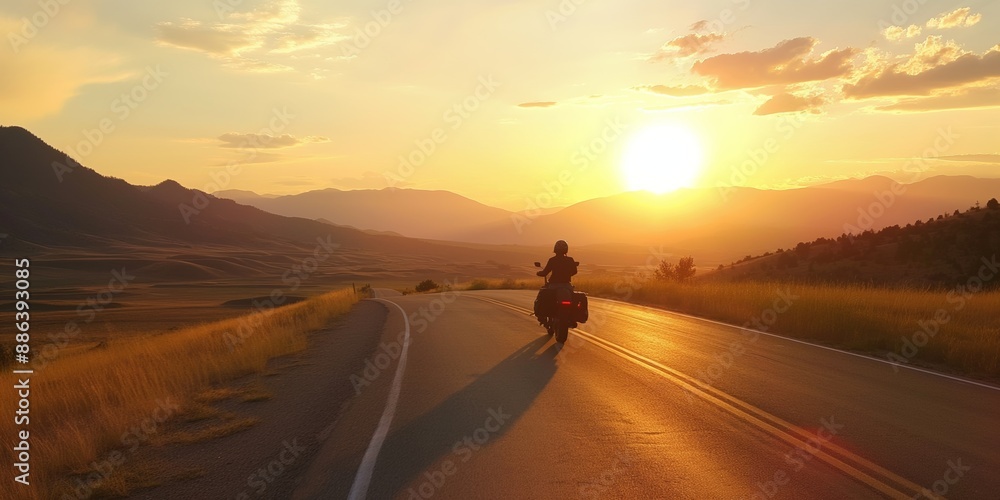 A man is riding a motorcycle down a road at sunset. The sky is orange and the sun is setting. The road is empty and the rider is the only person in the scene A man is riding a motorcycle down a road at sunset. The sky is orange and the sun is setting. The road is empty and the rider is the only person in the scene
