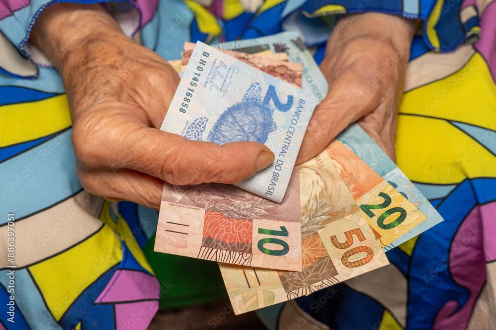 Pensioner's finances. An old woman counts Brazilian money, Pension and budget of elderly people in Brazil.