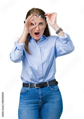 Beautiful middle age mature business woman wearing glasses over isolated background doing ok gesture shocked with surprised face, eye looking through fingers. Unbelieving expression.