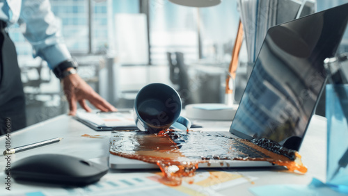 Obraz na plátně Clumsy Office Worker Accidentally Spilling Hot Coffee on Working Laptop Computer with Business Presentation Or Financial Reports For Large Company
