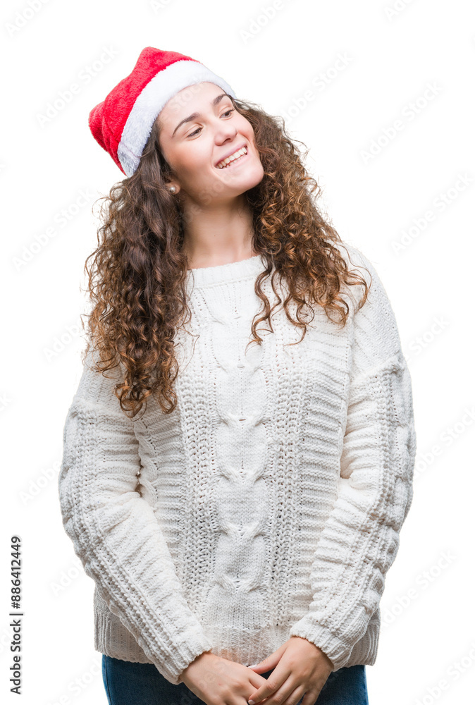 Young brunette girl wearing christmas hat over isolated background looking away to side with smile on face, natural expression. Laughing confident. Young brunette girl wearing christmas hat over isolated background looking away to side with smile on face, natural expression. Laughing confident.