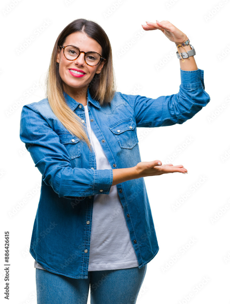 Young beautiful woman over wearing glasses over isolated background gesturing with hands showing big and large size sign, measure symbol. Smiling looking at the camera. Measuring concept. Young beautiful woman over wearing glasses over isolated background gesturing with hands showing big and large size sign, measure symbol. Smiling looking at the camera. Measuring concept.