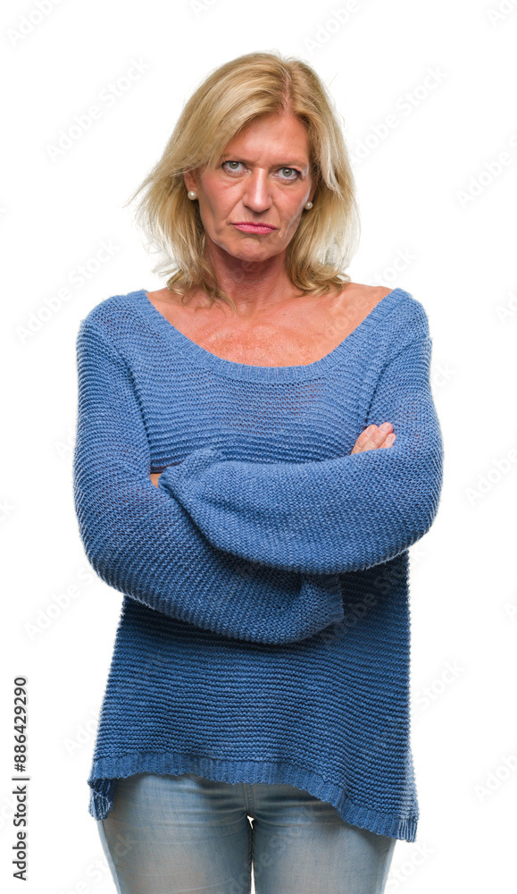 Middle age blonde woman wearing winter sweater over isolated background skeptic and nervous, disapproving expression on face with crossed arms. Negative person. Middle age blonde woman wearing winter sweater over isolated background skeptic and nervous, disapproving expression on face with crossed arms. Negative person.