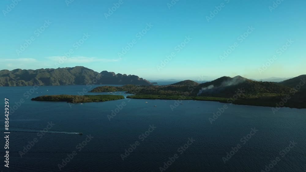 Experience a gentle descent over the tranquil waters near Banuang Daan Island, with the rugged landscape of Bancuan Island in the background. This drone footage captures the serene beauty of Coron's i Experience a gentle descent over the tranquil waters near Banuang Daan Island, with the rugged landscape of Bancuan Island in the background. This drone footage captures the serene beauty of Coron's i