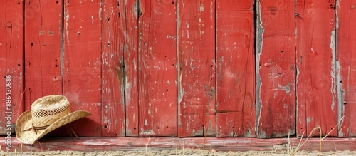 Aged straw cowboy hat resting against a weathered red barn wall with space for images. with copy space image. Place for adding text or design photo