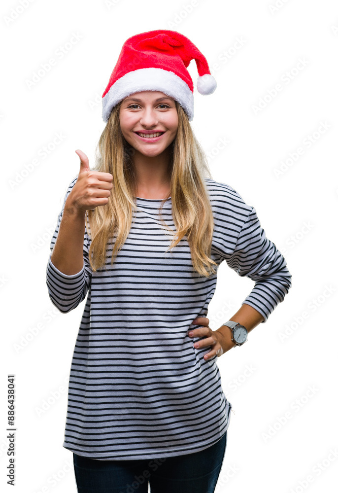 Young beautiful blonde woman wearing christmas hat over isolated background doing happy thumbs up gesture with hand. Approving expression looking at the camera with showing success. Young beautiful blonde woman wearing christmas hat over isolated background doing happy thumbs up gesture with hand. Approving expression looking at the camera with showing success.