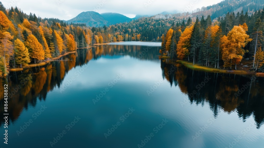 Fototapeta premium A beautiful autumn scene of a lake with vivid foliage reflecting on the water. The background includes distant hills, highlighting the seasonal change and natural beauty.
