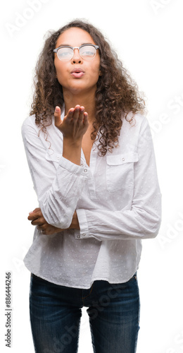 Beautiful young hispanic woman looking at the camera blowing a kiss with hand on air being lovely and sexy. Love expression.