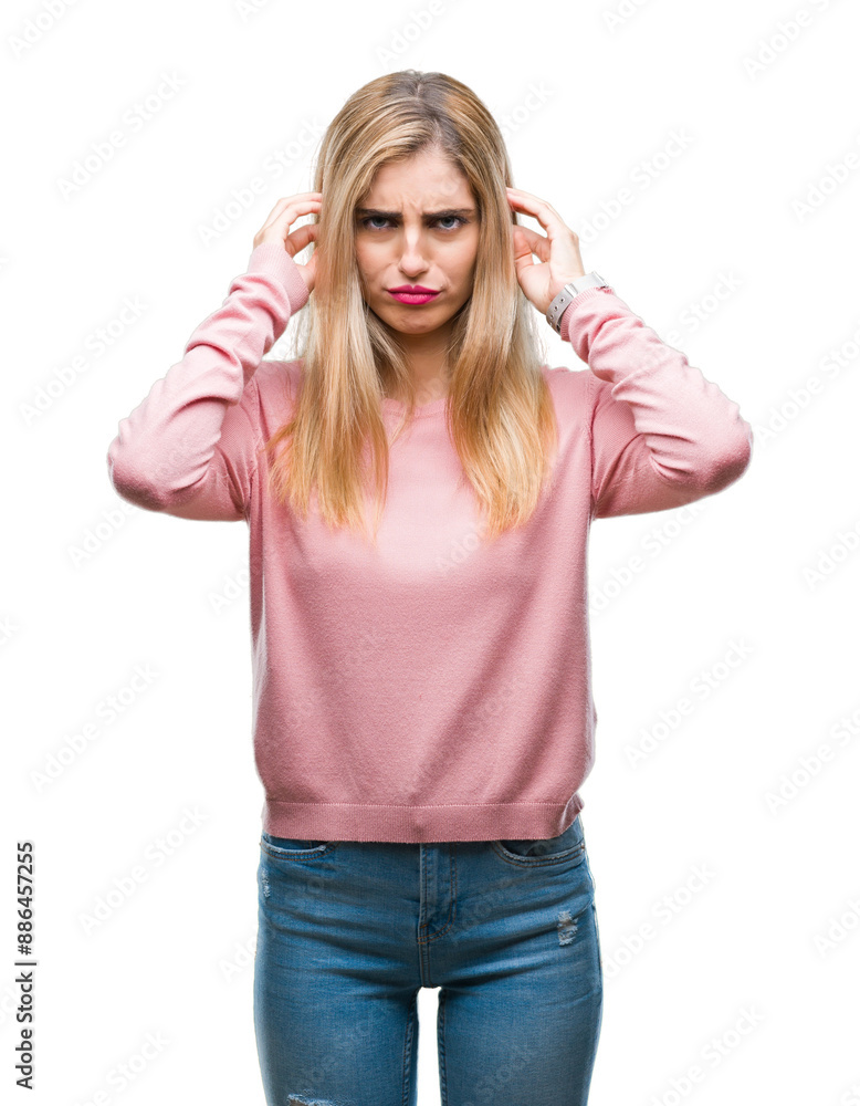 Young beautiful blonde woman wearing pink winter sweater over isolated background covering ears with fingers with annoyed expression for the noise of loud music. Deaf concept. Young beautiful blonde woman wearing pink winter sweater over isolated background covering ears with fingers with annoyed expression for the noise of loud music. Deaf concept.