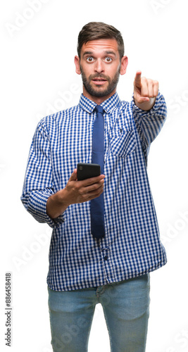 Young hadsome man texting sending message using smartphone over isolated background pointing with finger to the camera and to you, hand sign, positive and confident gesture from the front photo