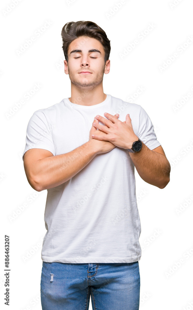Young handsome man wearing white t-shirt over isolated background smiling with hands on chest with closed eyes and grateful gesture on face. Health concept. Young handsome man wearing white t-shirt over isolated background smiling with hands on chest with closed eyes and grateful gesture on face. Health concept.