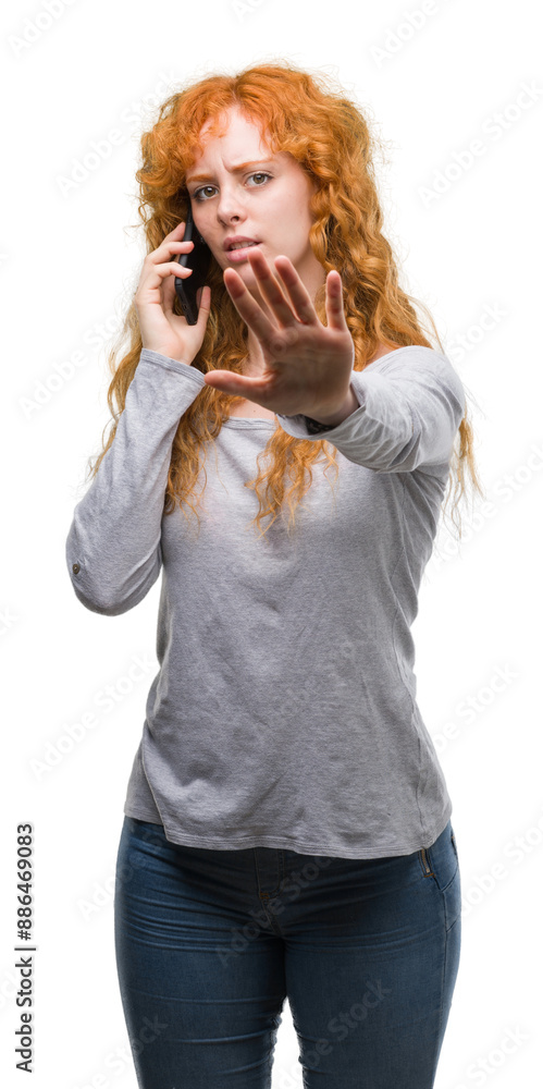 Young redhead woman talking on the phone with open hand doing stop sign with serious and confident expression, defense gesture Young redhead woman talking on the phone with open hand doing stop sign with serious and confident expression, defense gesture