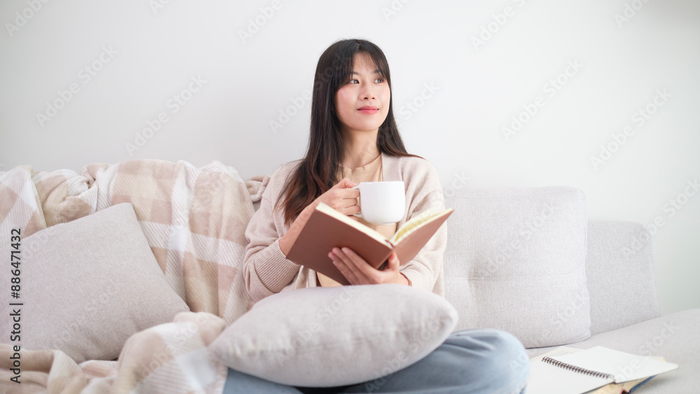 Relaxed young woman enjoying leisure time, resting on couch drinking mug of hot beverage and looking away. Relaxed young woman enjoying leisure time, resting on couch drinking mug of hot beverage and looking away.
