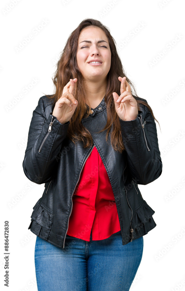 Beautiful plus size young woman wearing a fashion leather jacket over isolated background smiling crossing fingers with hope and eyes closed. Luck and superstitious concept. Beautiful plus size young woman wearing a fashion leather jacket over isolated background smiling crossing fingers with hope and eyes closed. Luck and superstitious concept.