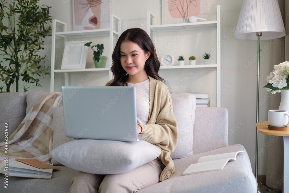 Smiling beautiful young woman sitting on couch and using laptop. Smiling beautiful young woman sitting on couch and using laptop.