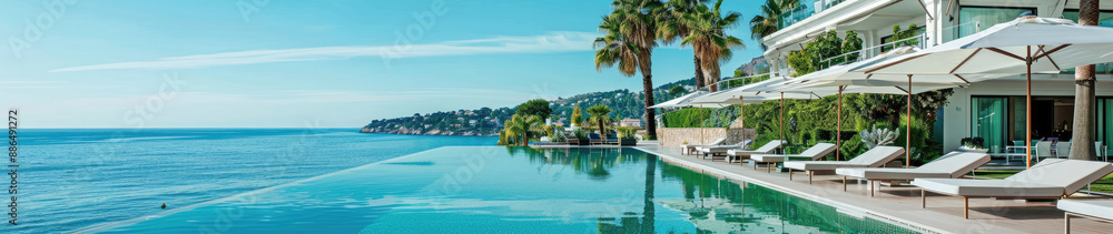 Fototapeta premium This stunning image captures the tranquility of a luxurious infinity pool overlooking the sea with a clear blue sky
