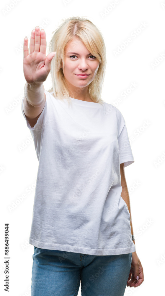 Obraz premium Young beautiful blonde woman wearing white t-shirt over isolated background doing stop sing with palm of the hand. Warning expression with negative and serious gesture on the face.