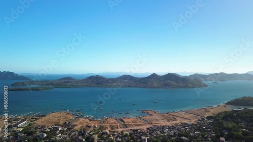 Explore the majestic aerial perspective of Bancuan Island in Coron, Philippines. This drone footage provides a breathtaking view of the rugged mountains, serene waters, and the bustling local communit photo