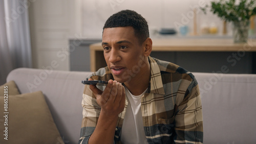 Fotografie Happy African American man at home couch sofa biracial male ethnic guy using cel