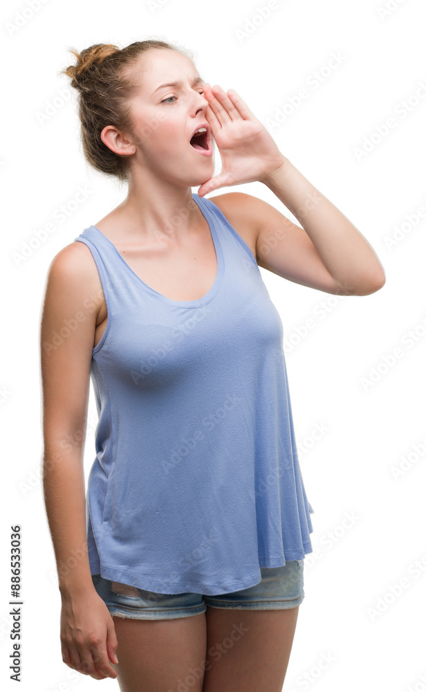 Young blonde woman shouting and screaming loud to side with hand on mouth. Communication concept. Young blonde woman shouting and screaming loud to side with hand on mouth. Communication concept.