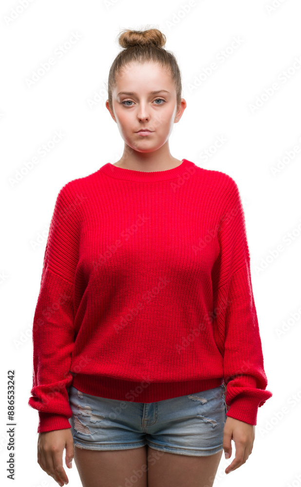 Young blonde woman wearing bun and red sweater with serious expression on face. Simple and natural looking at the camera. Young blonde woman wearing bun and red sweater with serious expression on face. Simple and natural looking at the camera.