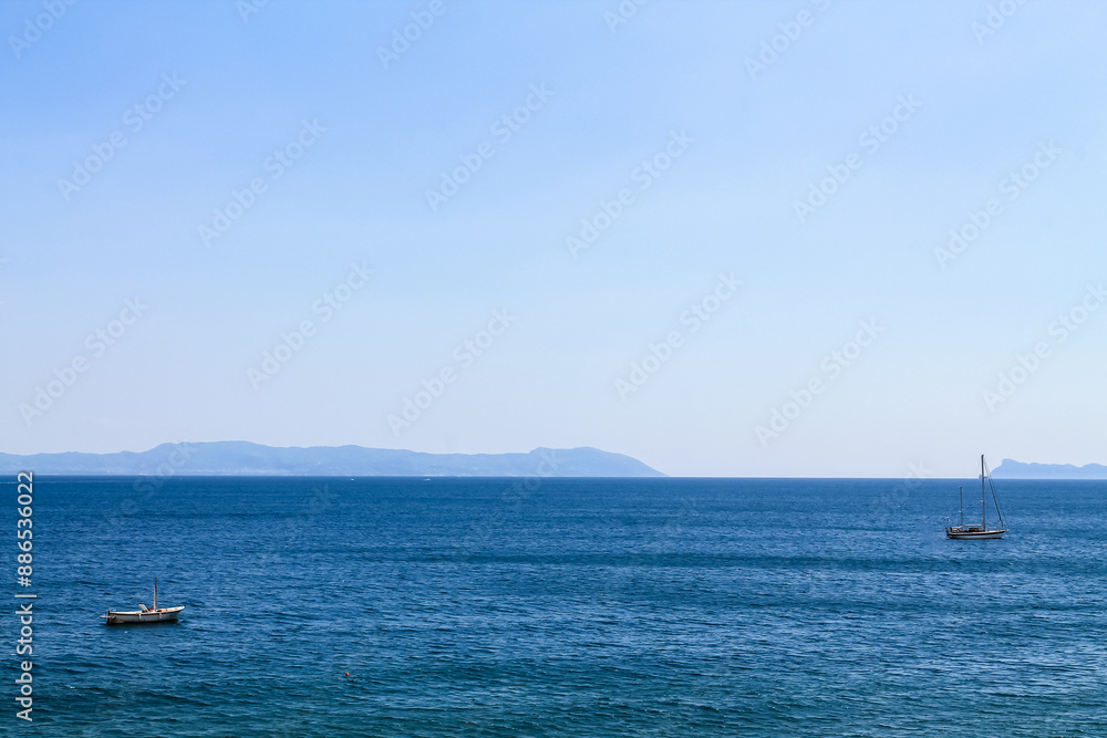 Two sailboats on the sea on the mountains background in Italy, the Bay of Naples Two sailboats on the sea on the mountains background in Italy, the Bay of Naples