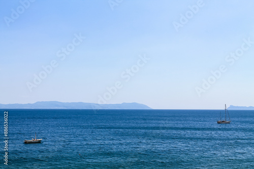 Two sailboats on the sea on the mountains background in Italy, the Bay of Naples