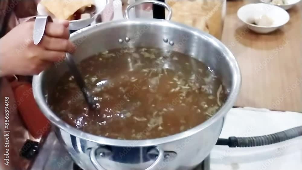 hand scooping up a hot soup stock from the pot. enjoying the meal time together with friend hand scooping up a hot soup stock from the pot. enjoying the meal time together with friend