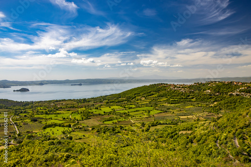 The enchanting panorama of Lake Bolsena, seen from the panoramic terrace of the ancient medieval village of Montefiascone, Viterbo, Italy. Mist on the horizon on a summer evening.
