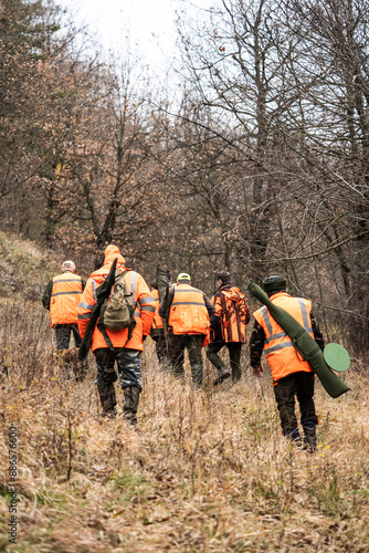 Fotografie Group of hunters wearing orange safety vests walking through the autumn forest