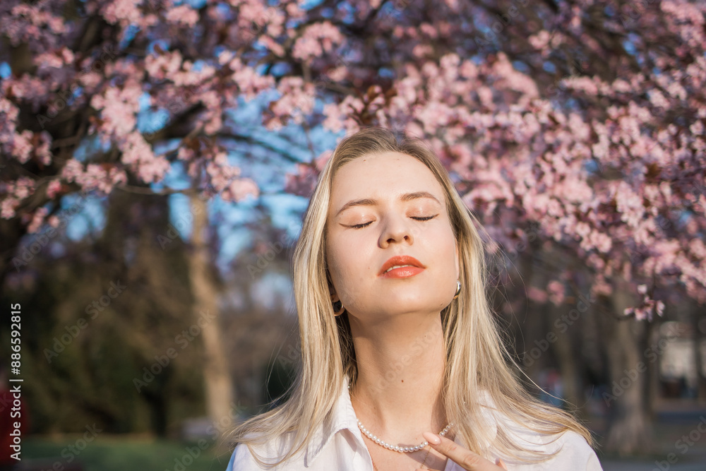 Fashion outdoor photo of beautiful woman with blond hair in elegant suit posing in spring flowering park with blooming cherry tree. Copy space and empty place for advertising text Fashion outdoor photo of beautiful woman with blond hair in elegant suit posing in spring flowering park with blooming cherry tree. Copy space and empty place for advertising text