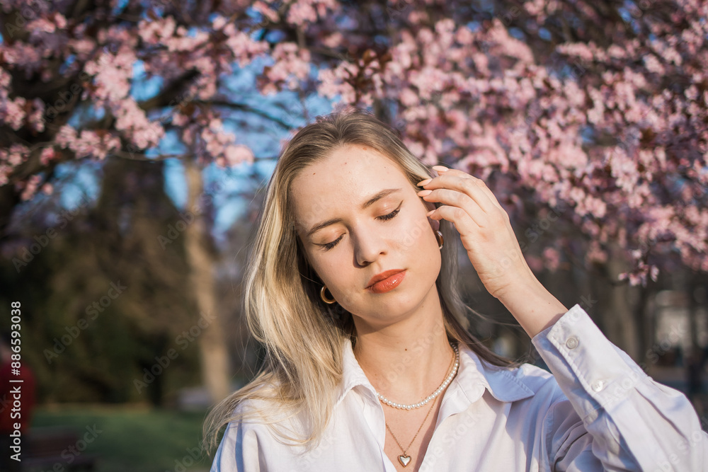 Fashion outdoor photo of beautiful woman with blond hair in elegant suit posing in spring flowering park with blooming cherry tree. Copy space and empty place for advertising text Fashion outdoor photo of beautiful woman with blond hair in elegant suit posing in spring flowering park with blooming cherry tree. Copy space and empty place for advertising text