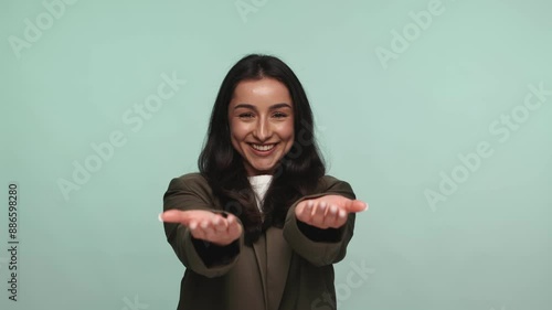 An unrecognizable woman extending her hands forward in a welcoming, inviting gesture against a turquoise background. photo