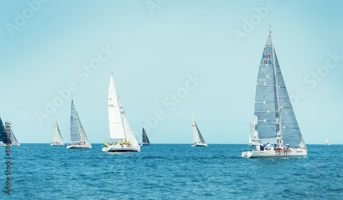 Sailboats races in regatta near Brindisi under blue sky. Crew members working together on deck