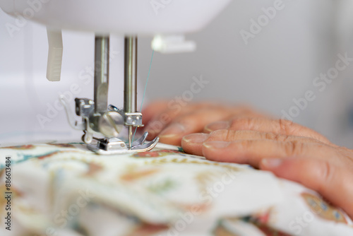 Unrecognizable hands sewing patterned fabric with a sewing machine, focusing on her task. Concept of sewing craftsmanship. photo