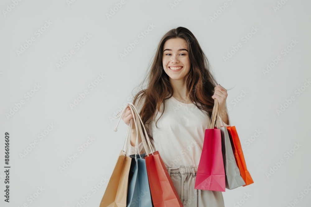 A woman holding multiple shopping bags smiling at the camera. Happy with the low price offered during sale. A woman holding multiple shopping bags smiling at the camera. Happy with the low price offered during sale.